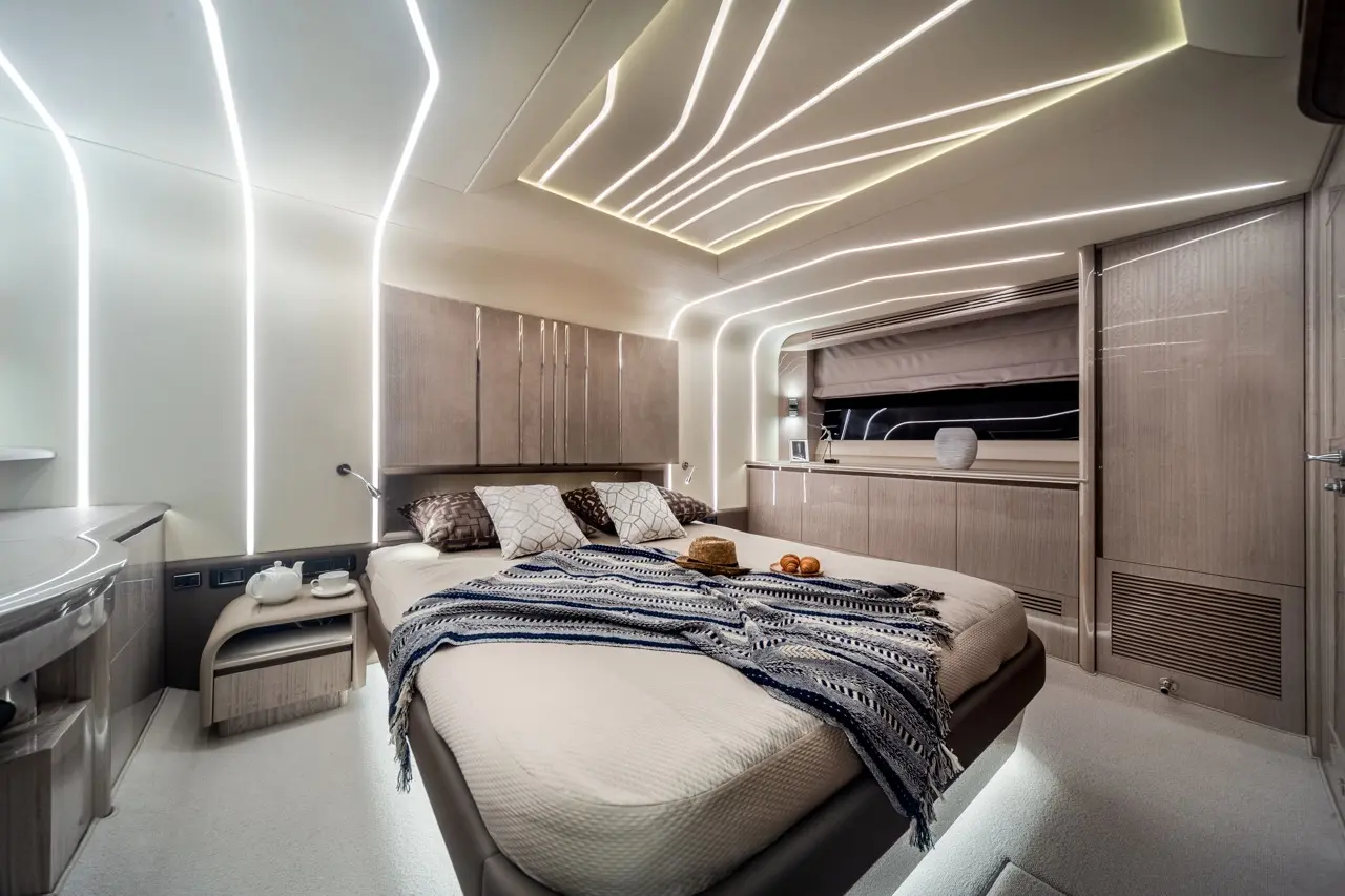 Modern bedroom with ambient lighting, a large bed adorned with cushions and a blanket, and a small table with tea set.