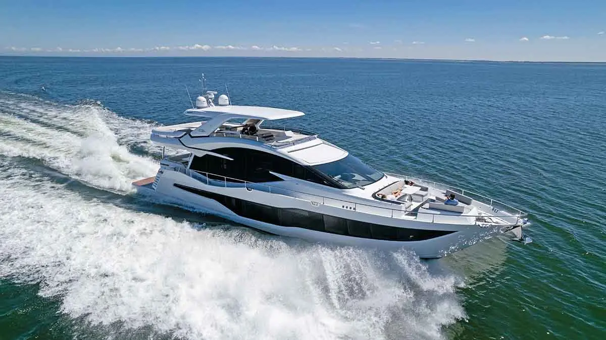 Luxury motor yacht gliding through bright blue water, with passengers relaxing on deck. Waves splashing against the hull.