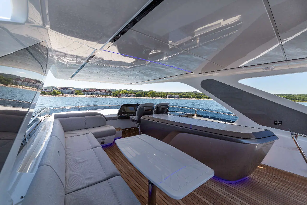 Luxurious yacht interior with a sleek design, featuring a curved sofa, table, and scenic views of the waterfront.