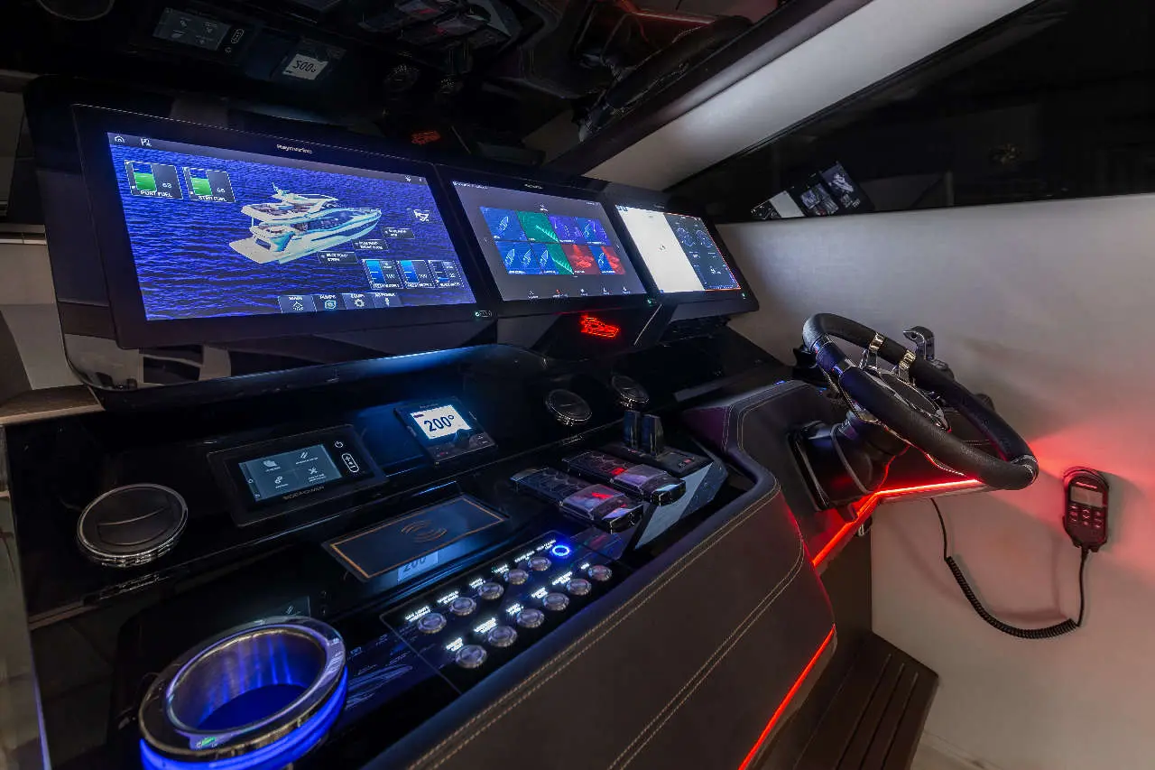 Modern yacht control panel featuring multiple screens, navigation controls, and ambient lighting in a sleek design.
