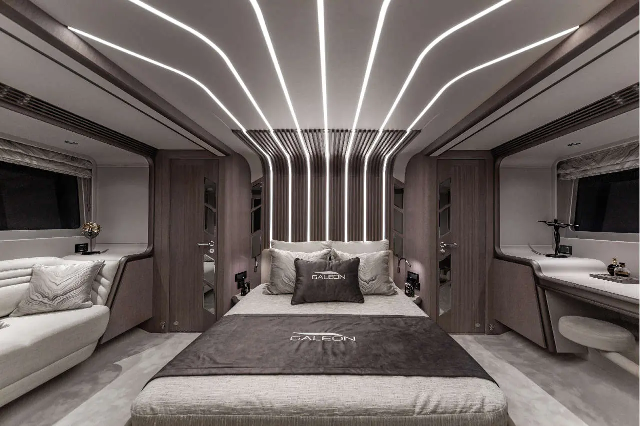 Modern yacht bedroom with sleek lighting, plush bedding, and a decorative pillow featuring the 