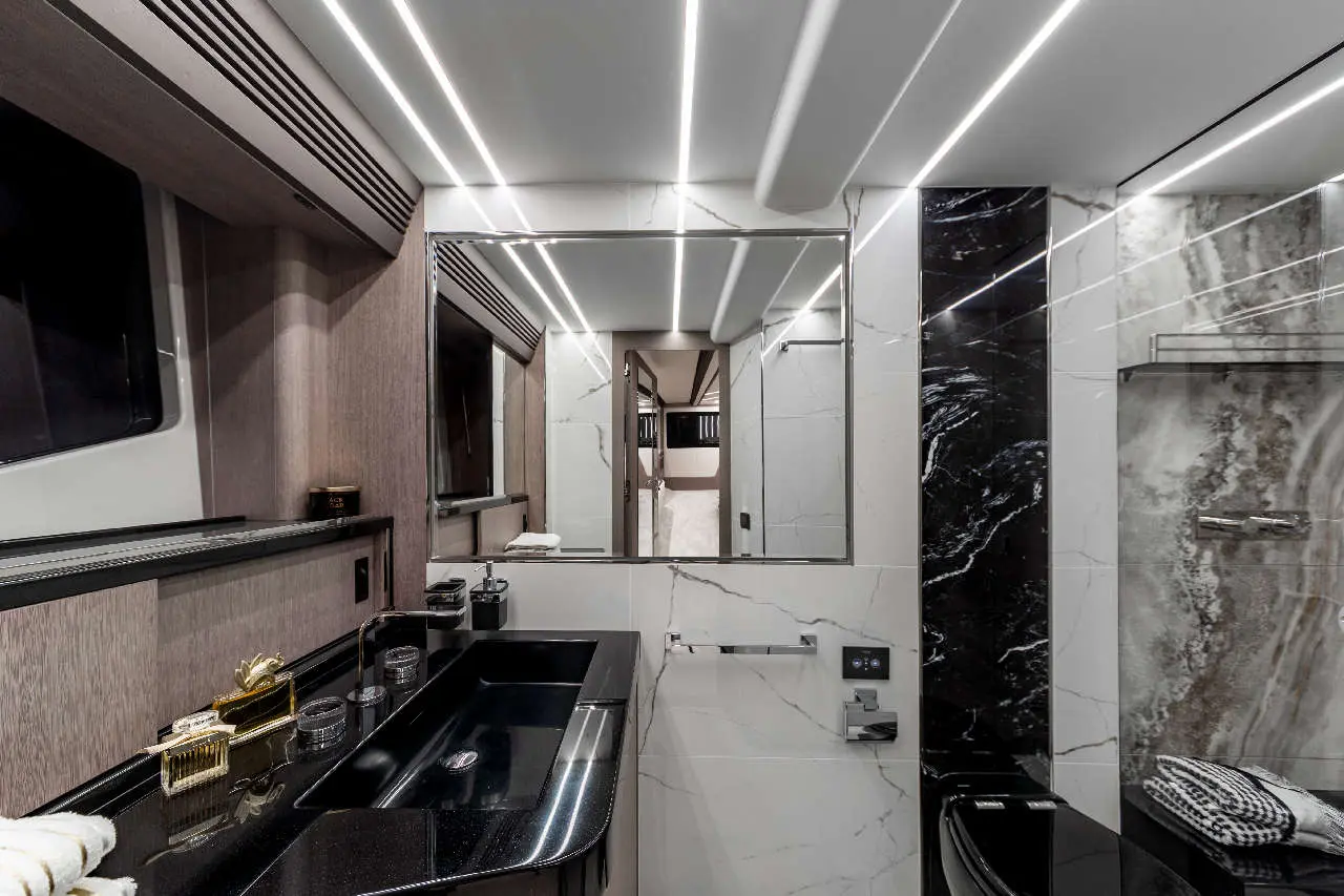 Sleek modern bathroom featuring black sink, marble walls, ambient lighting, and a large mirror reflecting the space.