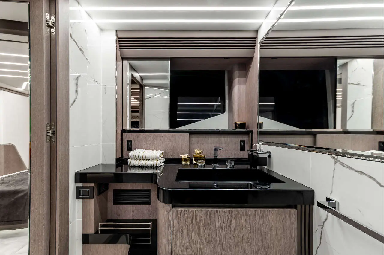 Luxury bathroom with a black countertop, towels, and sleek mirrors, featuring modern lighting and elegant design elements.