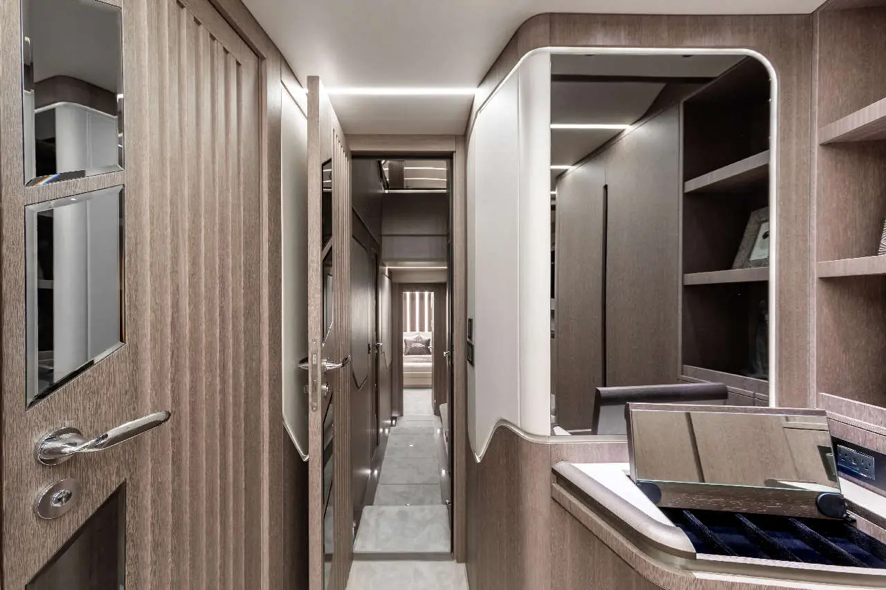 Modern corridor in a stylish interior, featuring wooden paneling, a mirror, and a spacious view towards a bedroom.