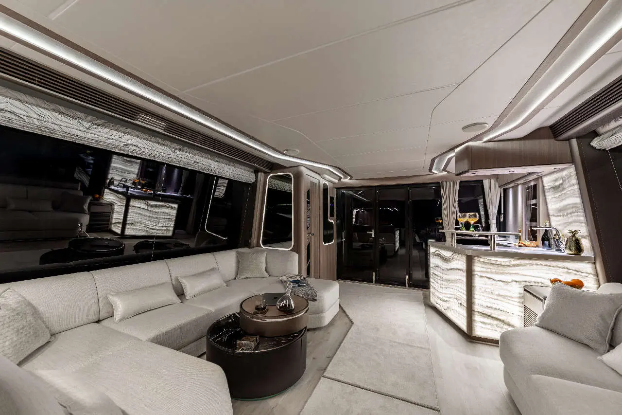 Luxurious yacht interior featuring a modern lounge area, marble bar, and panoramic windows, illuminated by soft lighting.
