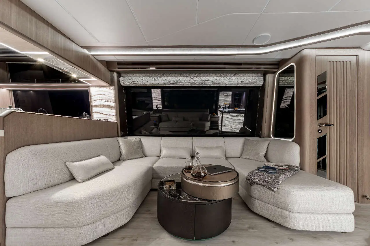 Luxurious yacht interior featuring a spacious beige sofa, stylish coffee table, and large windows with scenic views.