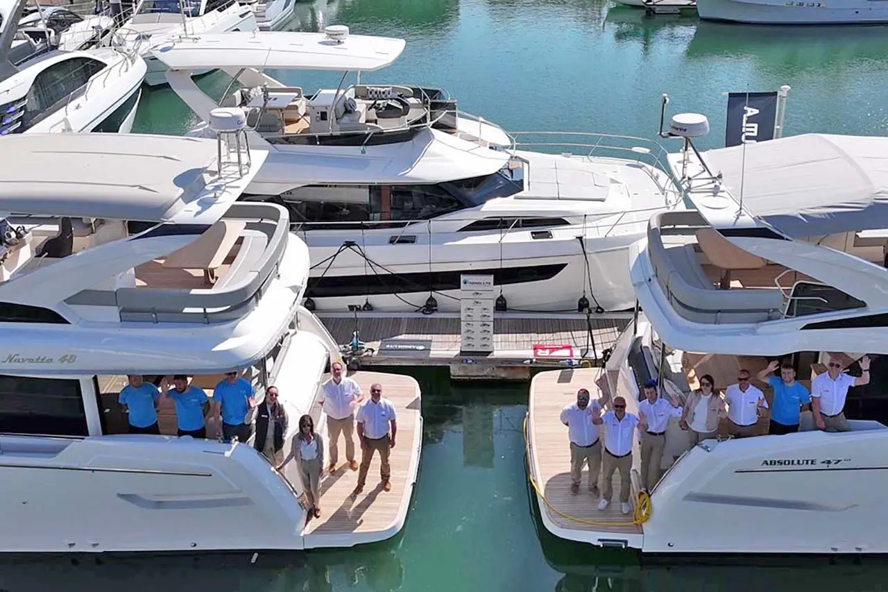 Two luxurious yachts at a marina with smiling crews, labelled 