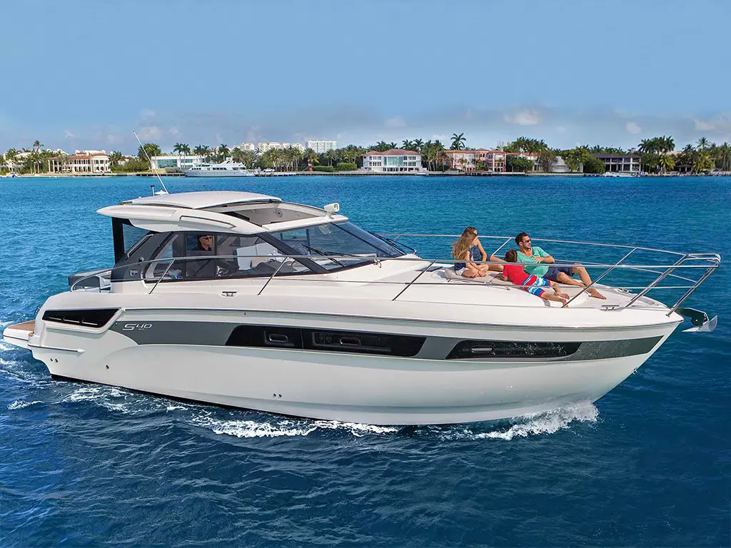 A sleek motorboat glides through blue waters, with people relaxing on the deck, surrounded by luxury homes.