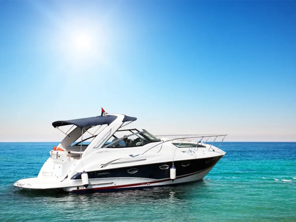 A luxury motorboat anchored in clear blue waters under a bright sun, showcasing a pristine coastal scene.