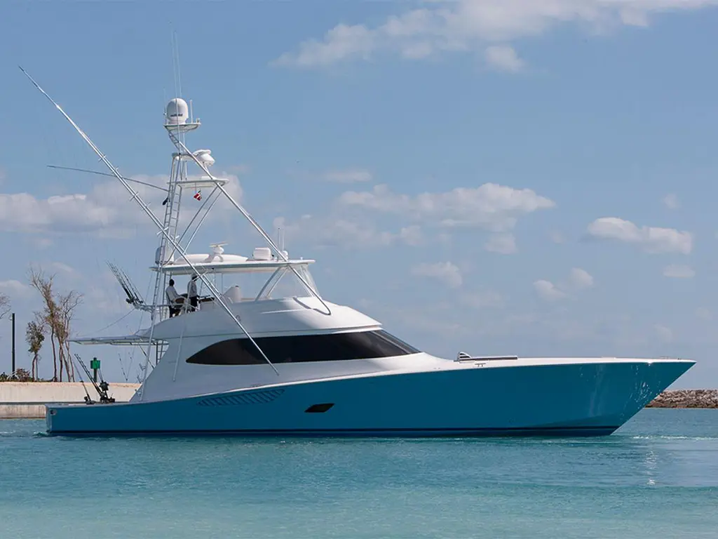 A sleek white and turquoise yacht is anchored in calm blue waters under a clear sky with scattered clouds.