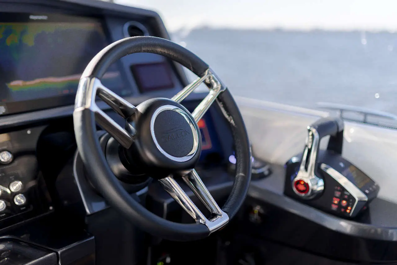 Boat dashboard featuring a sleek steering wheel, a throttle control, and a digital screen reflecting navigational data.