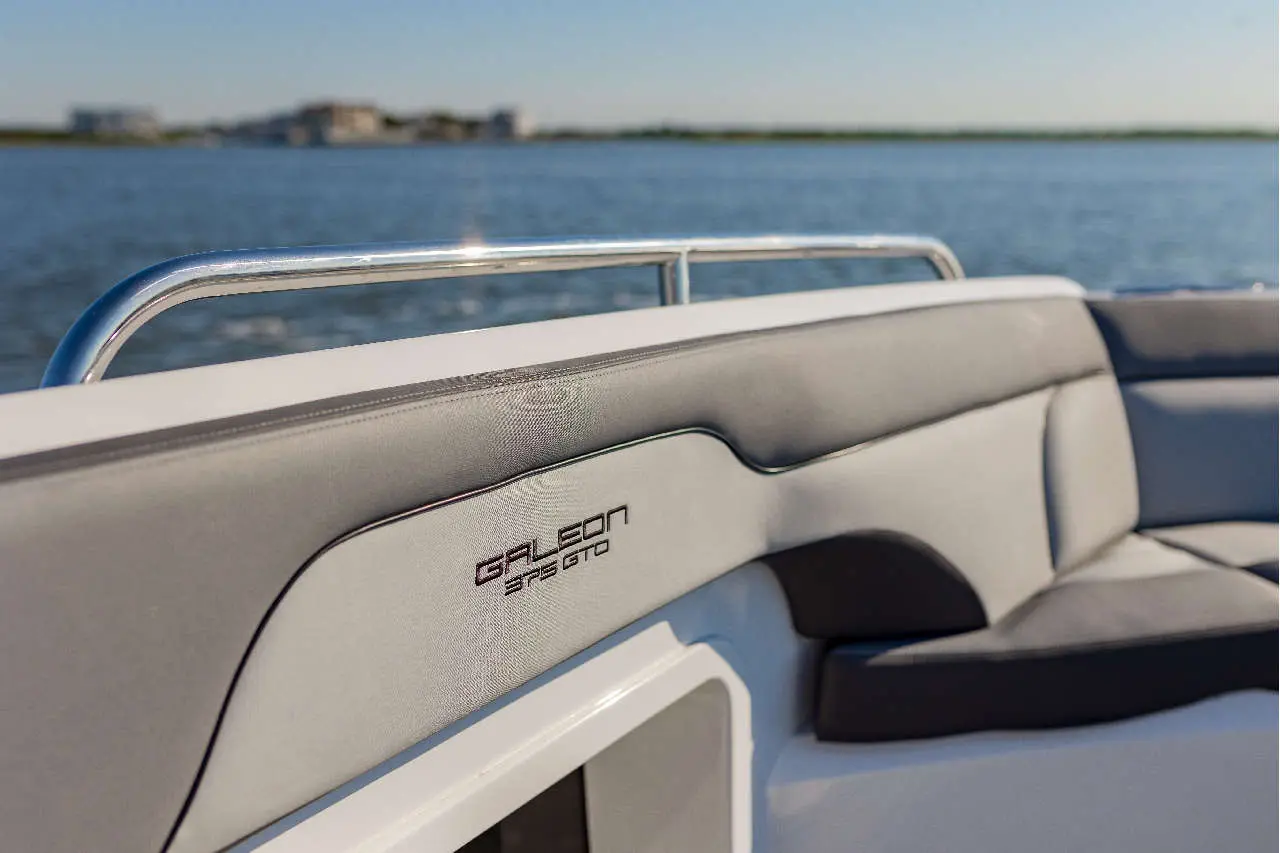 Galeon 325 GTO boat interior featuring a sleek grey seat and metallic handrail, with a serene water backdrop.