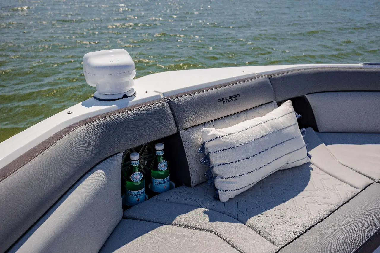 Luxurious boat seating with a striped cushion, featuring two bottled drinks nestled in the grey upholstery by the water.