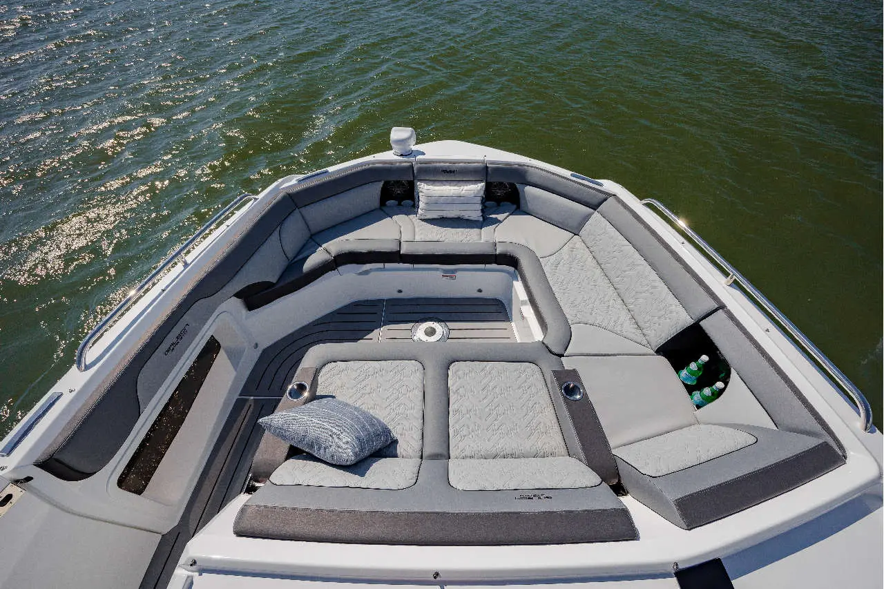 Luxury boat seating area with grey cushions, a decorative pillow, and green drinks visible on the right, overlooking water.