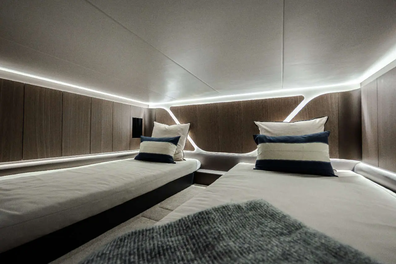 Stylish cabin with two narrow beds, soft pillows, and modern lighting, showcasing contemporary interior design.