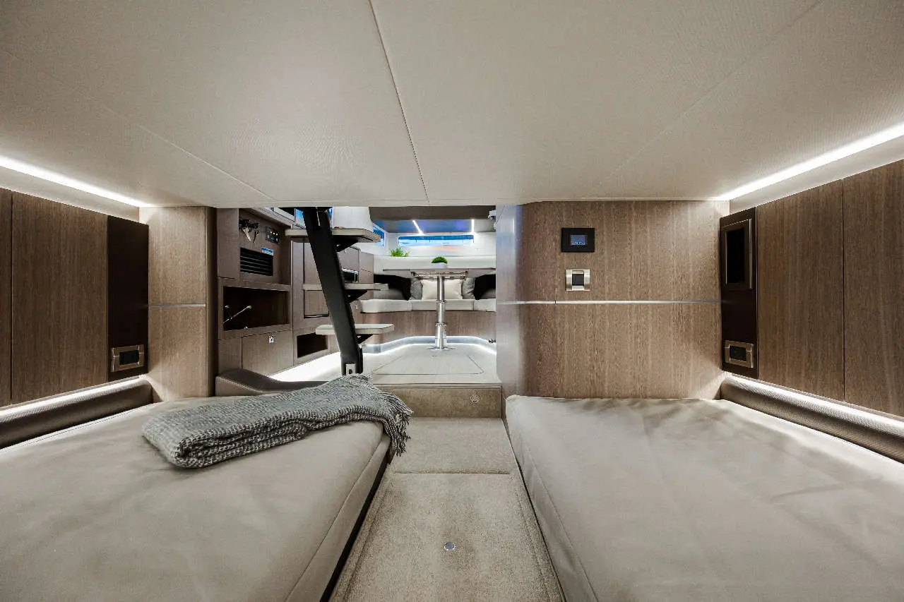 Modern cabin interior with two single beds, sleek decor, lighting, and a table in the background for relaxation and dining.