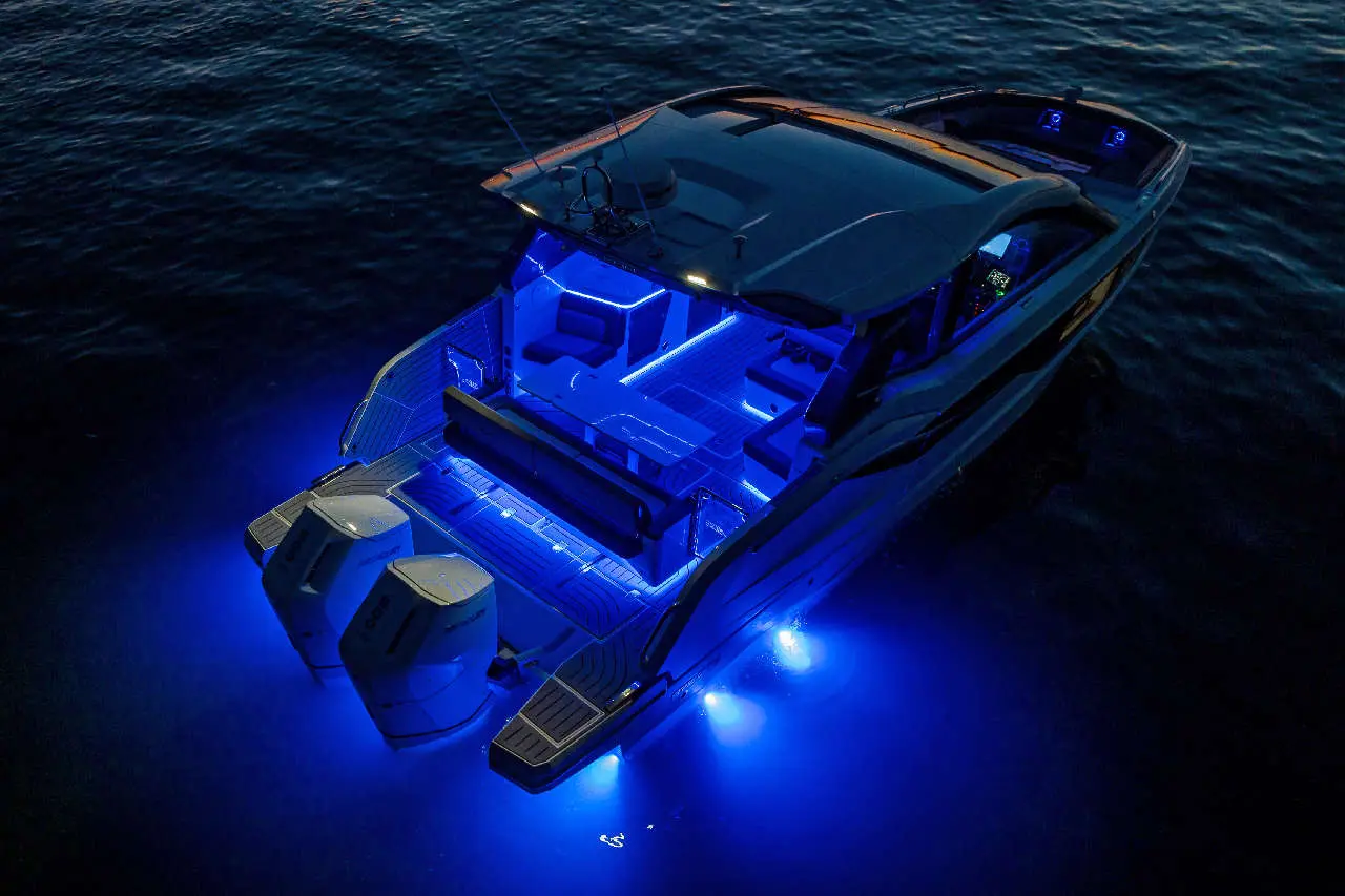 Luxury boat lit with blue LED lights, showcasing sleek design and spacious deck, floating on calm water at night.