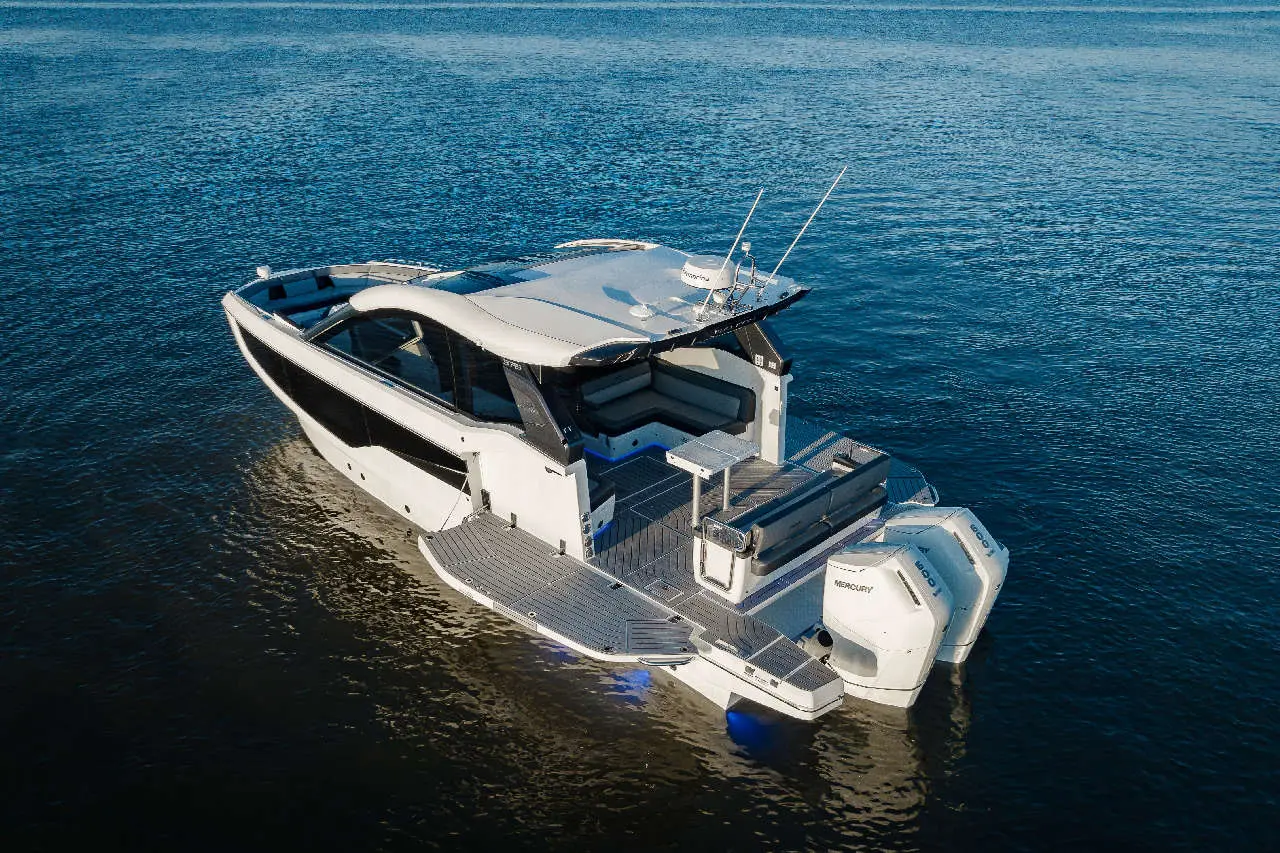 Luxury motorboat on calm waters, featuring modern design and seating area, with visible Mercury engines at the stern.