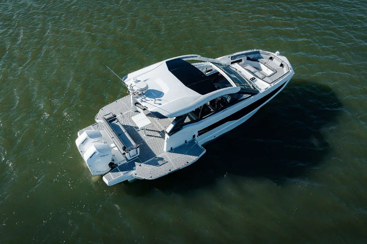 Aerial view of a sleek white motor yacht on blue-green water, showcasing its modern design and spacious deck areas.