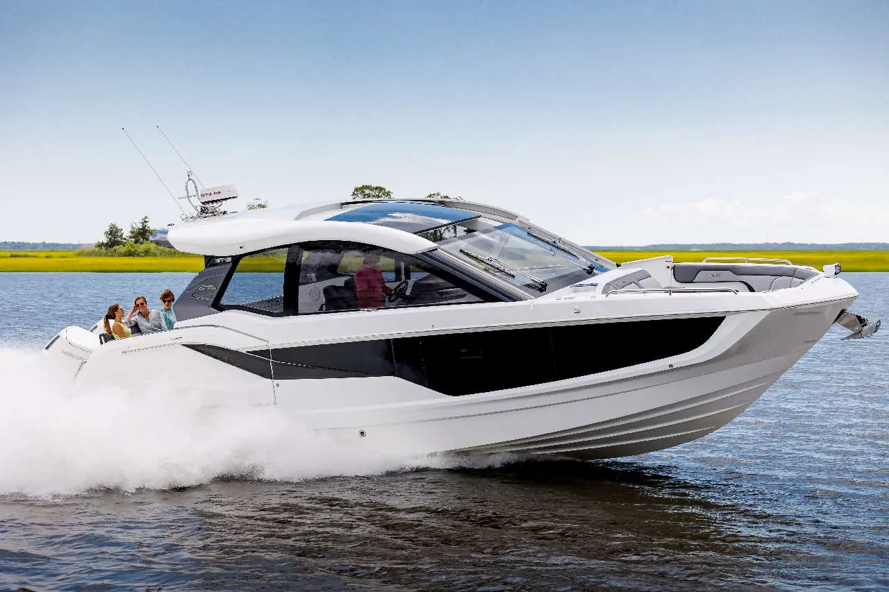 A sleek white motorboat speeds through calm waters, carrying four passengers, with green wetlands in the background.