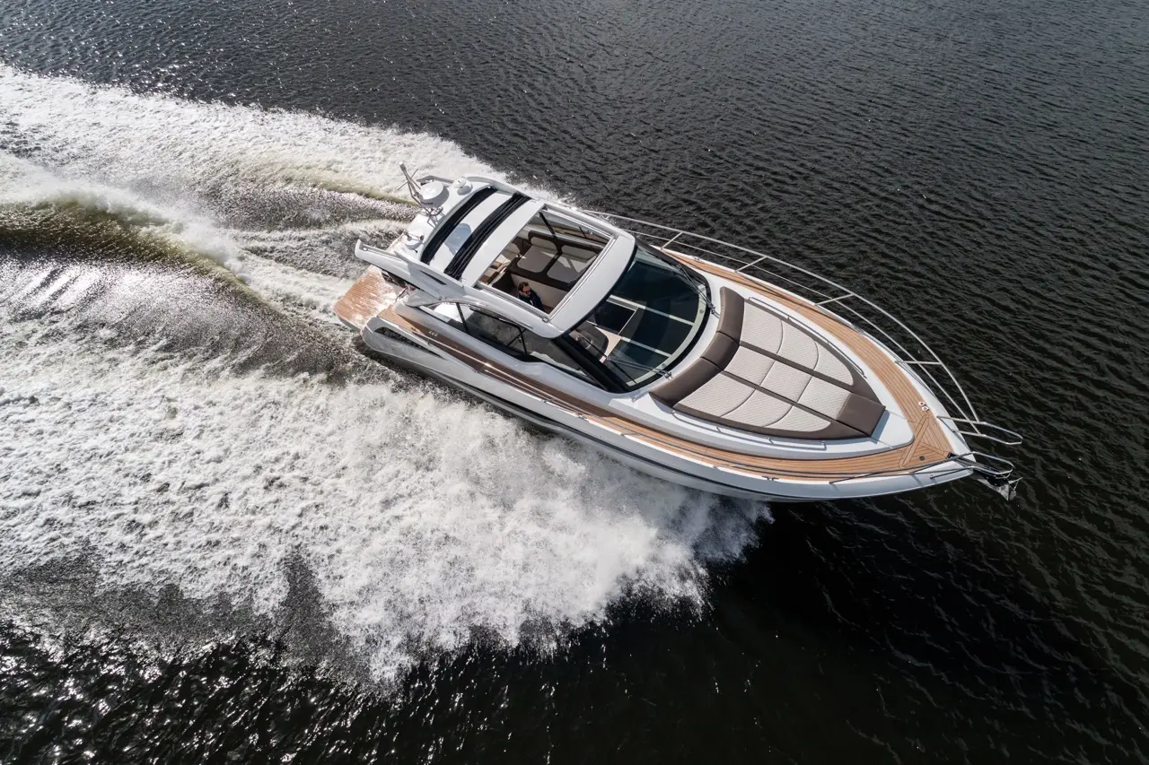 Luxury powerboat speeding through water, creating a wake, with a panoramic cockpit and spacious sun deck.