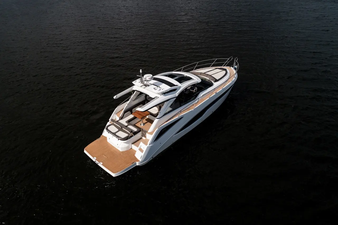 Luxury motor yacht on dark water, featuring a spacious deck, sleek design, and modern styling. Perfect for leisure cruising.