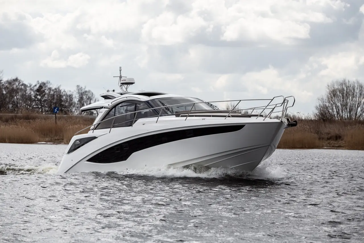 A sleek white motorboat navigating a lake, with rippling water and a cloudy sky in the background, showcasing modern design.