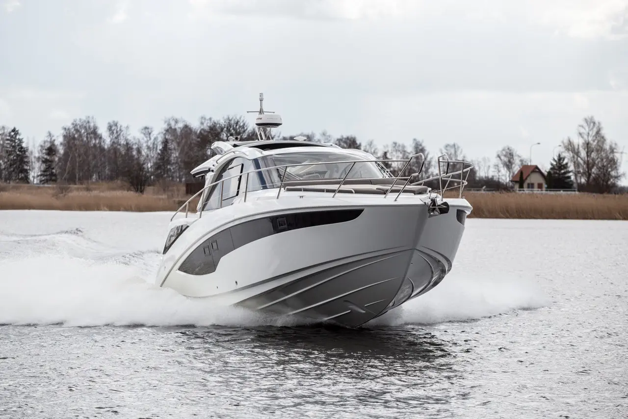 A sleek white motorboat navigating quickly across a serene water surface, trailing splashes behind.