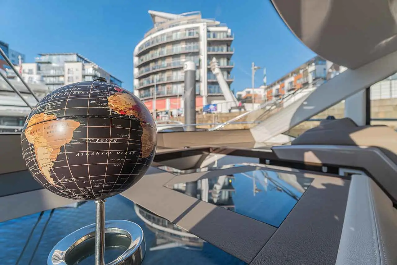 A decorative globe showing South America and the Atlantic Ocean on a yacht with modern buildings in the background.