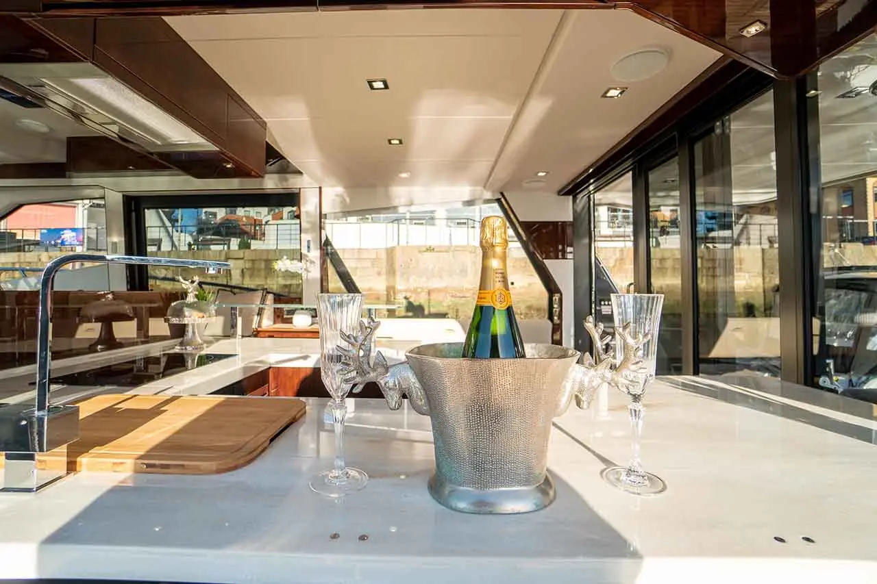 Luxury yacht interior featuring a champagne bottle in a silver bucket, with crystal glasses on a white countertop.