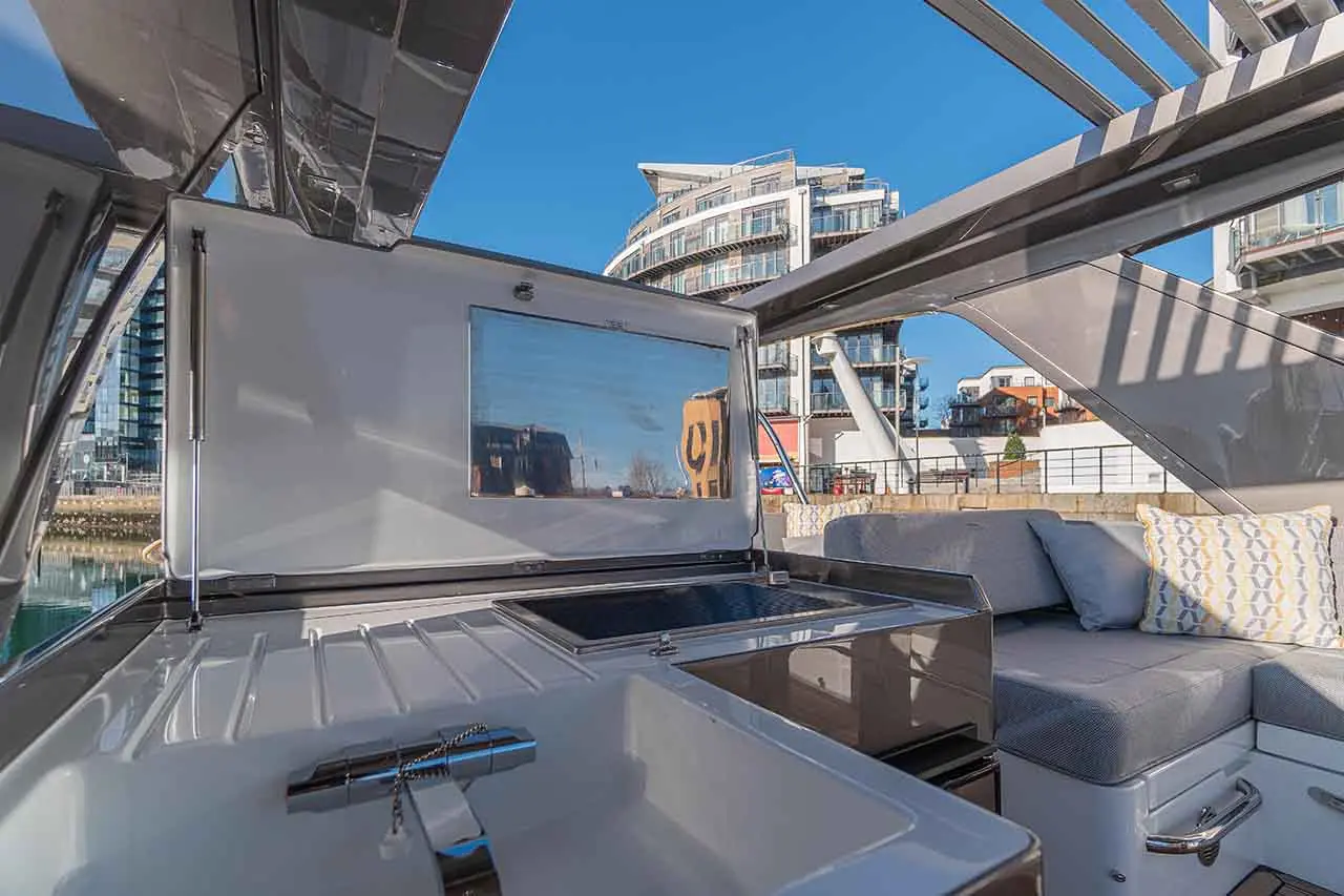 Modern boat interior showcasing a sleek kitchen area, stylish seating, and a view of contemporary buildings and water.