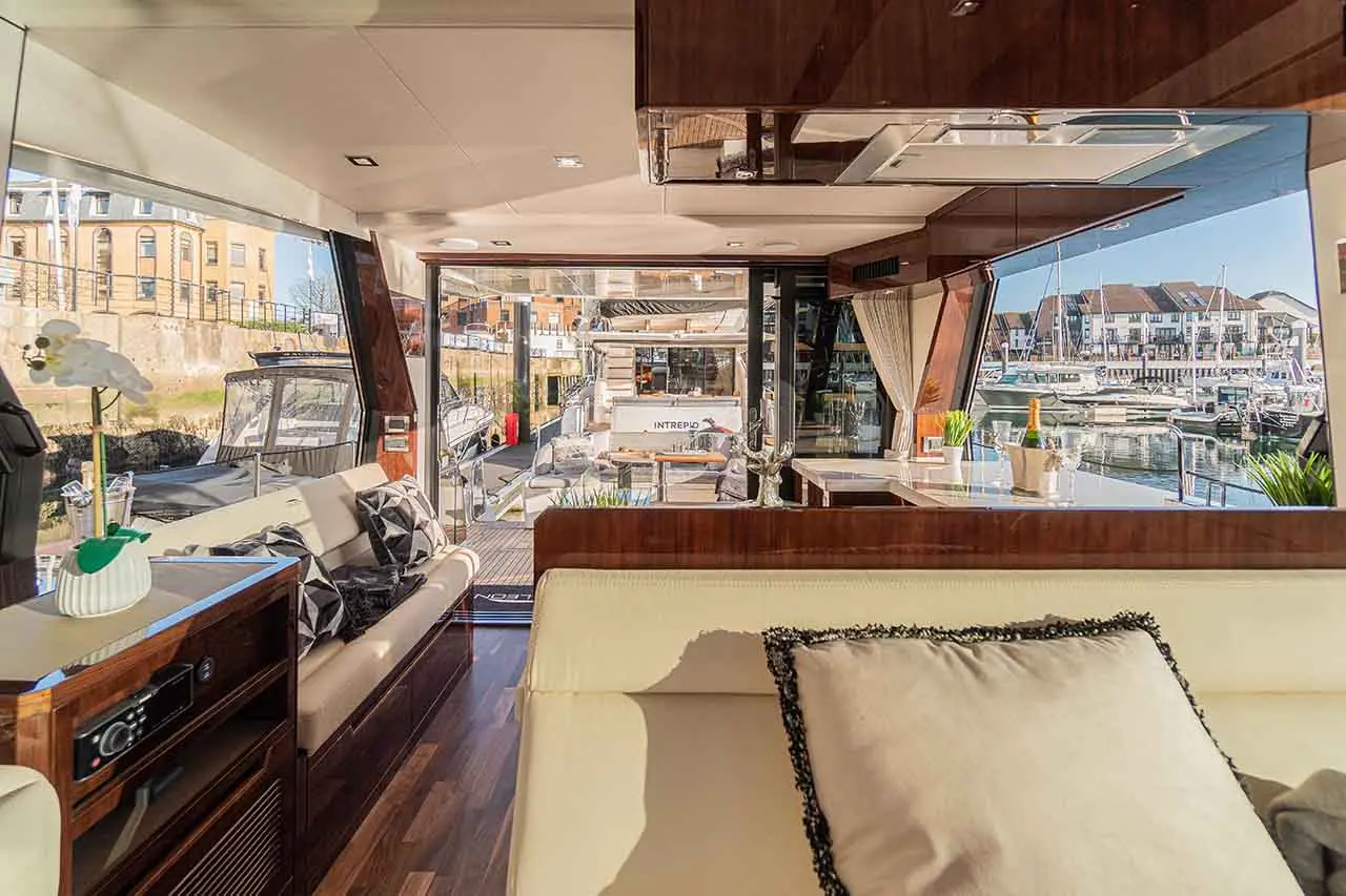 Luxury yacht interior with panoramic views of a marina, featuring elegant furnishings and modern decor.