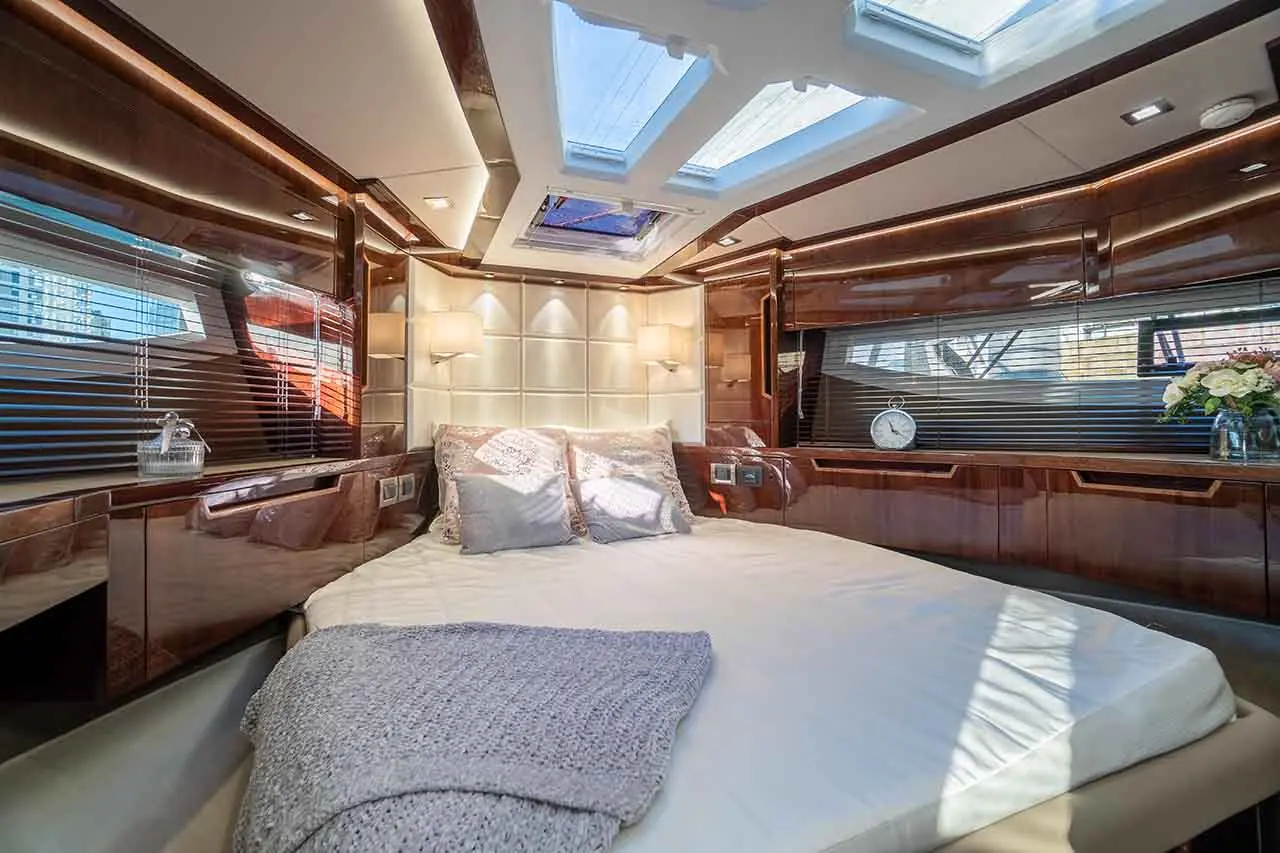 Luxurious boat cabin featuring a double bed, polished wood finishes, skylights, and decorative pillows.