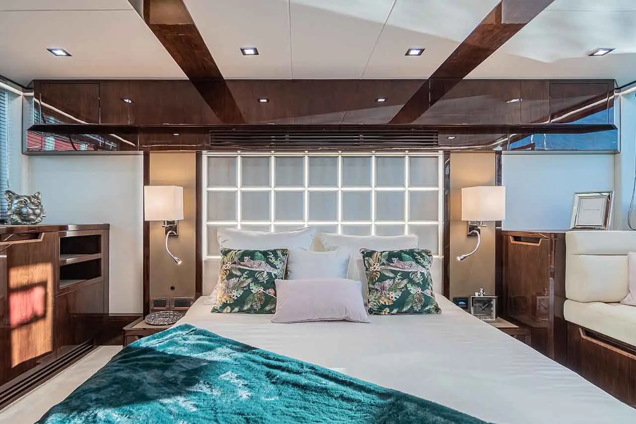 Luxurious yacht bedroom featuring a double bed, decorative pillows, elegant lighting, and wooden cabinetry.