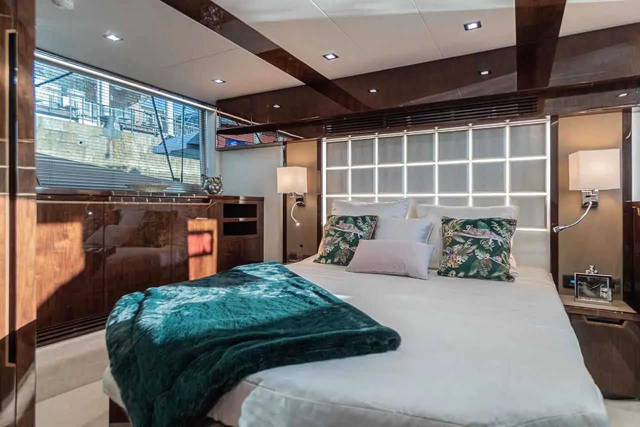 Luxurious boat interior featuring a stylish bedroom, king-size bed with decorative pillows, and large windows for natural light.