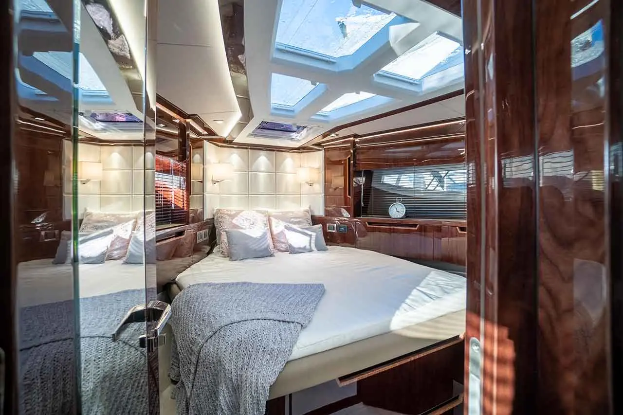 Luxury yacht bedroom featuring a double bed with decorative pillows, skylights, and polished wooden surfaces.