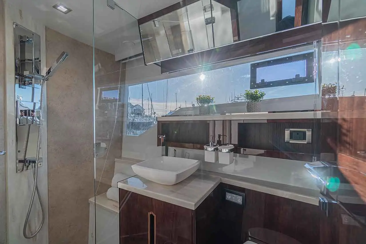 Modern bathroom with a vessel sink, shower, and marina view. Features plants and sleek cabinetry with mirrored accents.