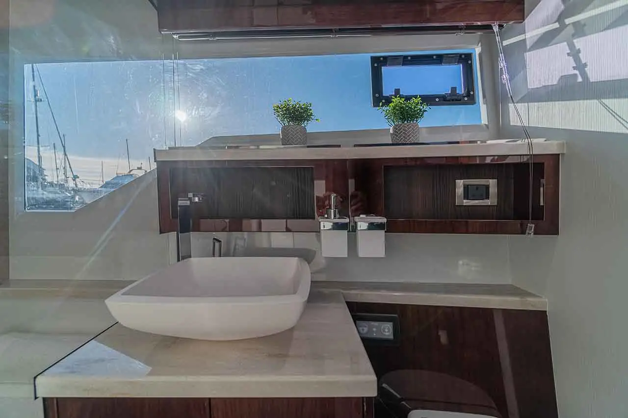 Modern bathroom interior with a large white basin, stylish cabinetry, and views of a marina through large windows.