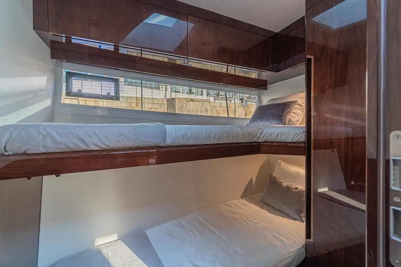 Compact cabin with two bunks, one above and one below, featuring modern decor and a window allowing natural light.