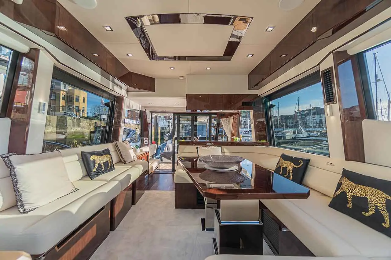 Stylish yacht interior featuring leather seating, a modern dining table, and views of the marina through large windows.