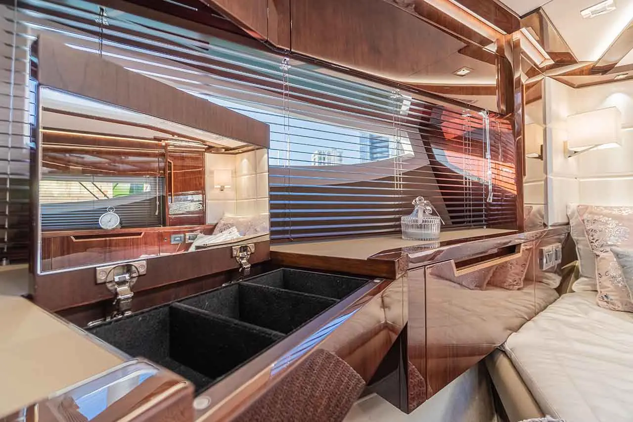 Luxurious cabin interior with polished wood, blinds, a clock, and a decorative vase on a bedside table.