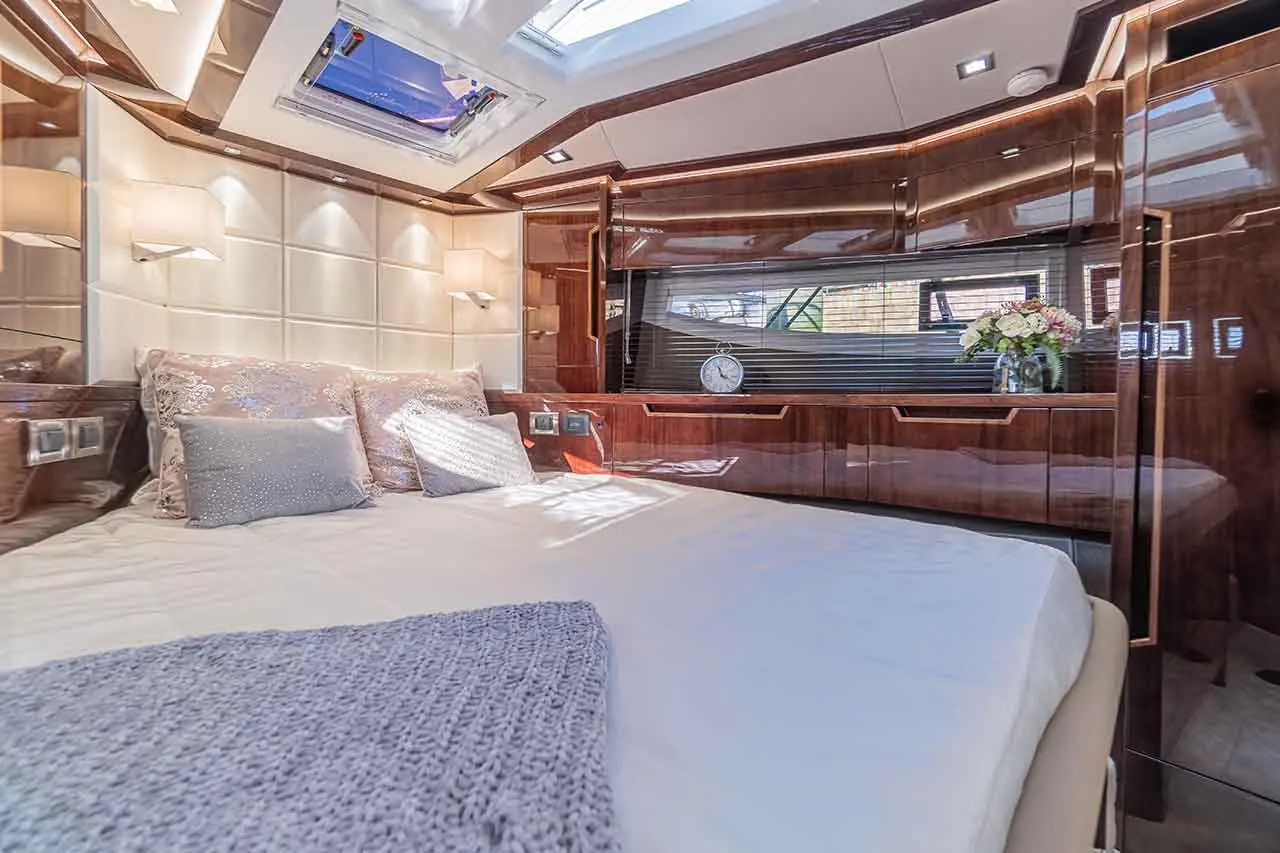 Luxurious yacht bedroom featuring a double bed, decorative pillows, modern furnishings, and natural light from the skylight.