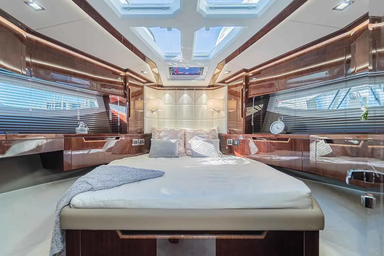 Luxurious yacht bedroom featuring a double bed, polished wood furnishings, large skylights, and elegant lighting details.