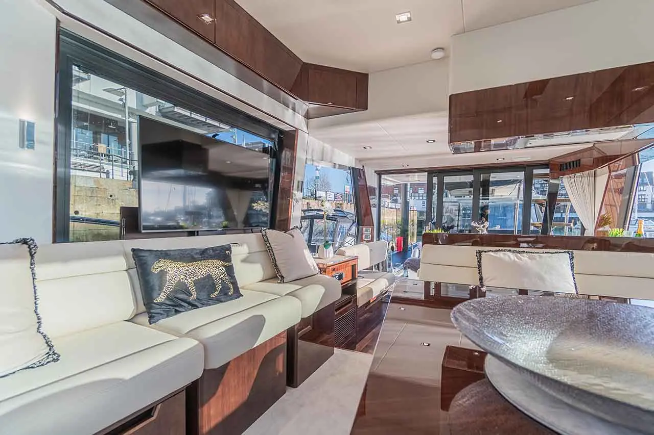 Luxury yacht interior showcasing a spacious lounge with white sofas, a decorative leopard print cushion, and large windows.