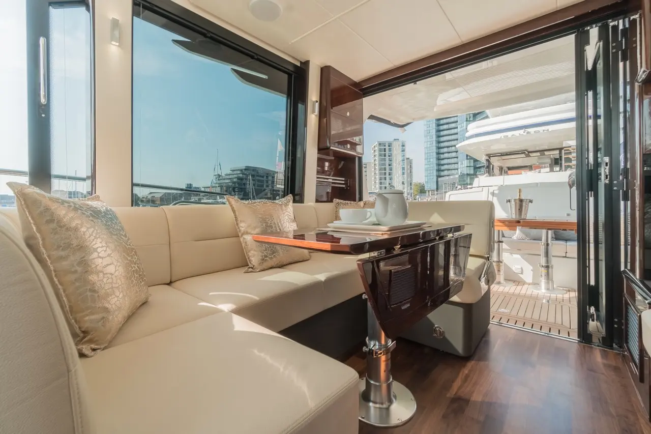 Bright and modern yacht interior featuring a cream sofa, polished table, and views of the city through large windows.