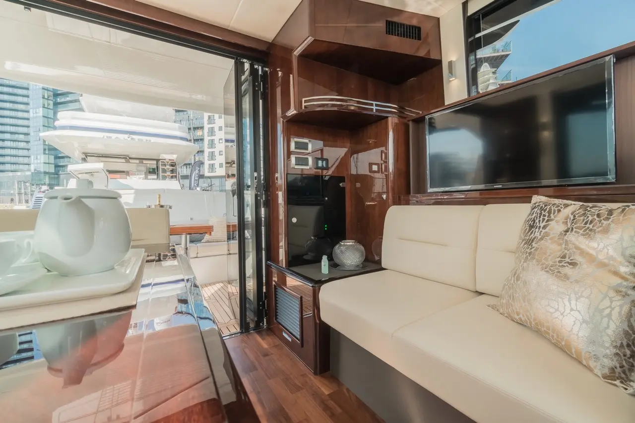 Interior of a yacht featuring a beige sofa, modern decor, and a view of another yacht through sliding glass doors.