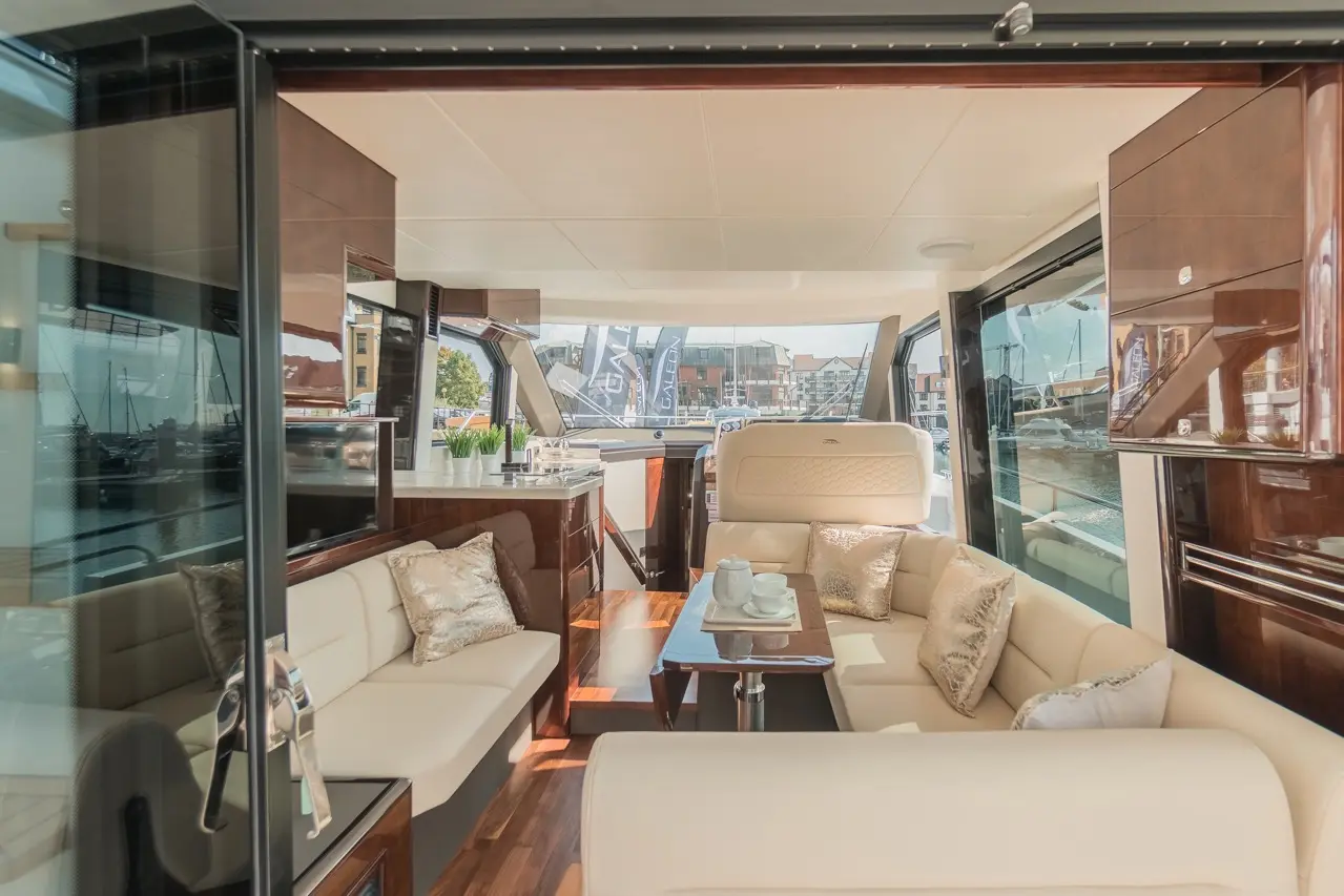 Luxurious yacht interior featuring plush seating, a coffee table, and views of the marina through large glass windows.