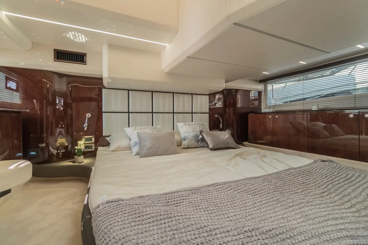 Luxurious yacht bedroom featuring a large bed, elegant cushions, and stylish wood cabinetry with ambient lighting.