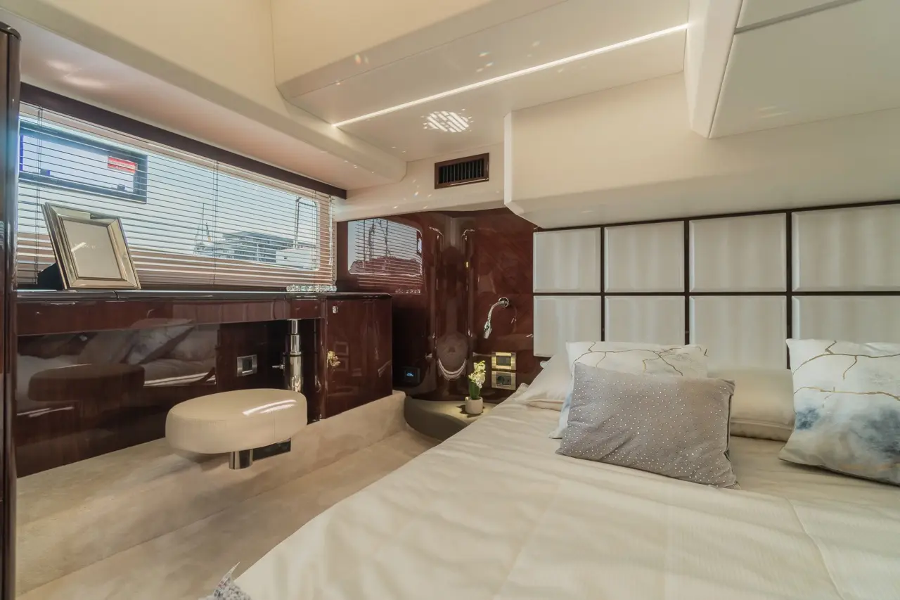Modern yacht cabin featuring a double bed, elegant decor, and windows with blinds, showcasing a luxurious boating experience.