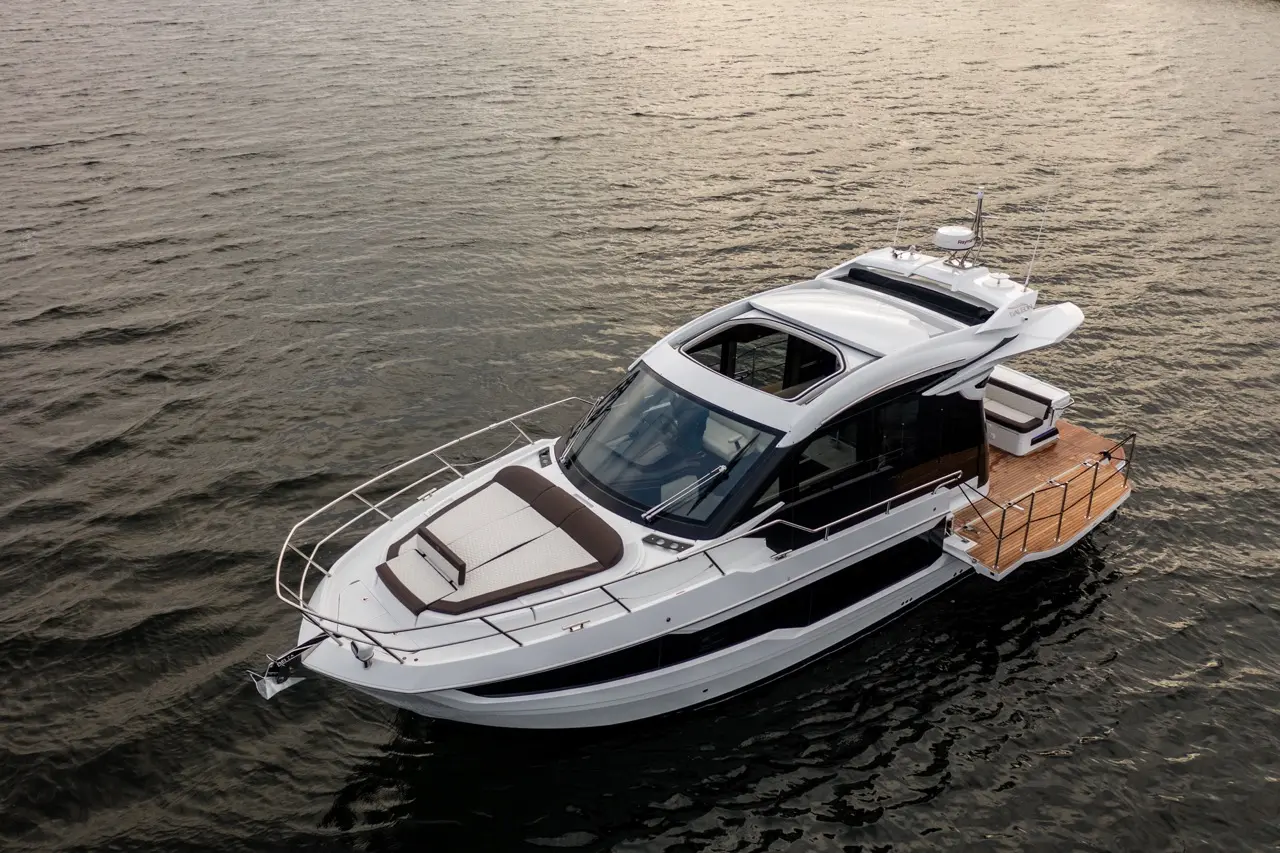 A luxury motorboat with a modern design floats on calm waters, featuring a spacious deck and sleek lines.